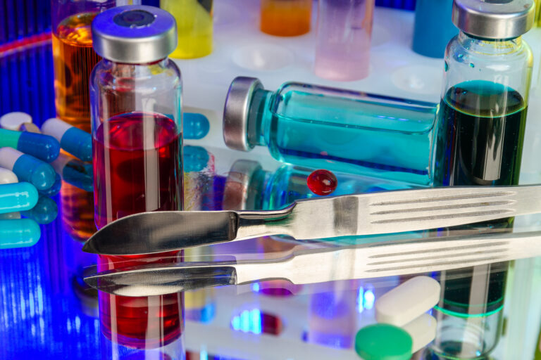 Close up lab bottles, pills, scalpel and other conventional medical items.
