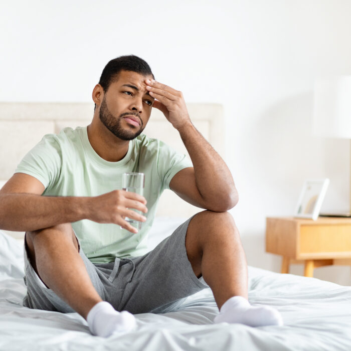 Man feeling fatigued while sitting on the edge of his bed, illustrating reduced energy associated with low testosterone.