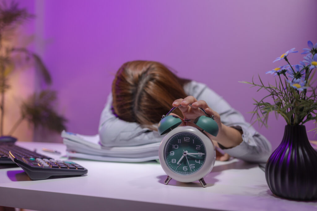 Woman asleep at her desk due to chronic stress and fatigue, highlighting the connection between poor sleep, cortisol, and hormone balance.