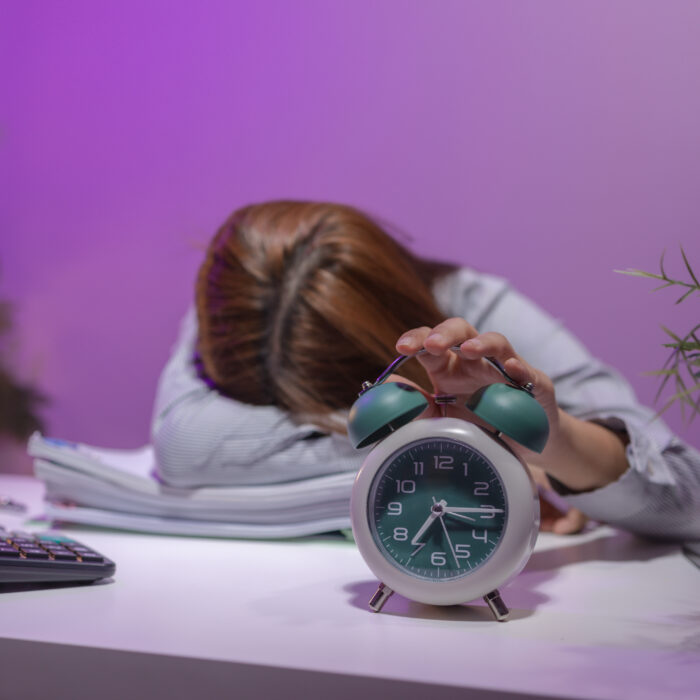 Woman asleep at her desk due to chronic stress and fatigue, highlighting the connection between poor sleep, cortisol, and hormone balance.