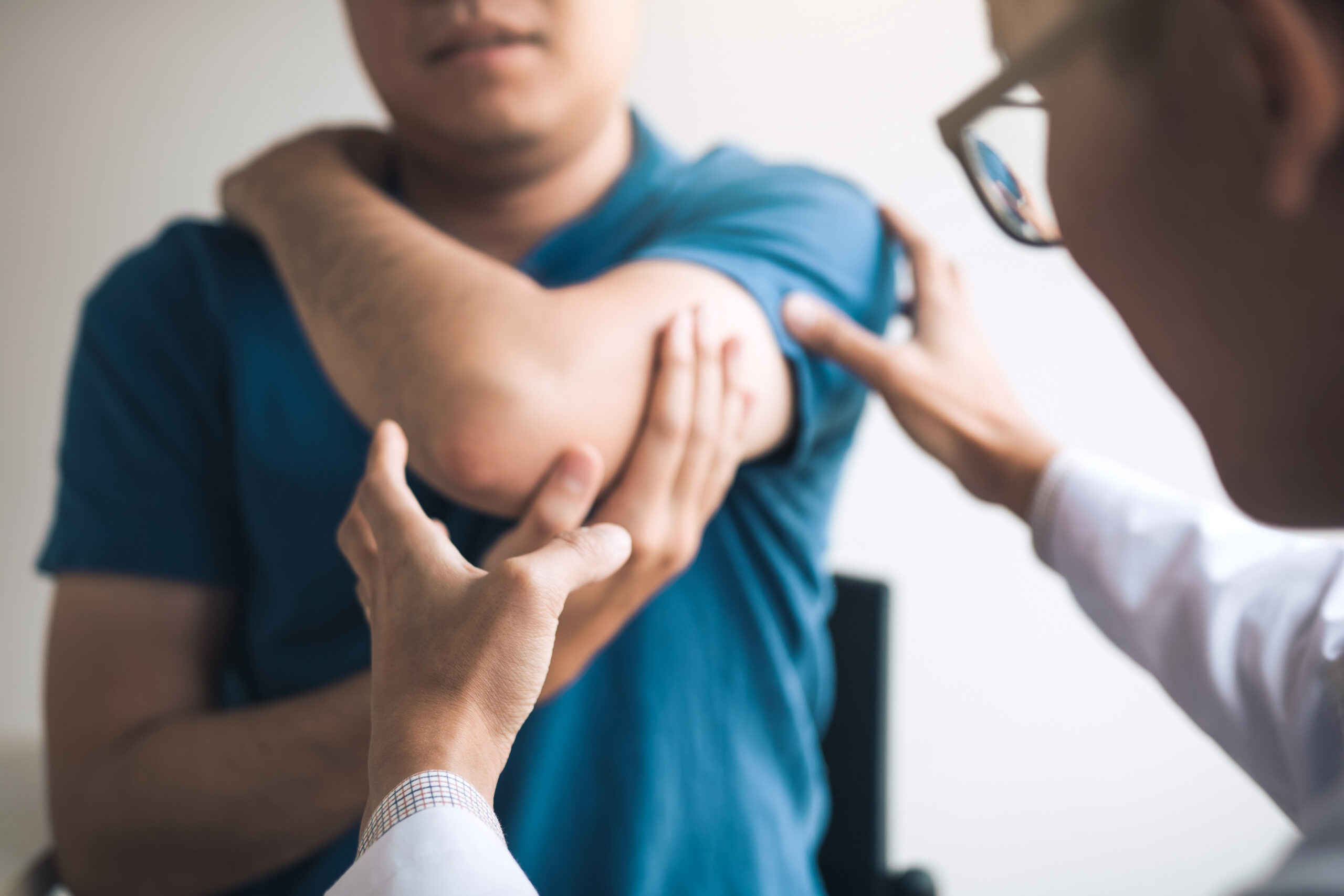 Doctor examining a patient’s elbow and arm to assess joint pain and musculoskeletal function.