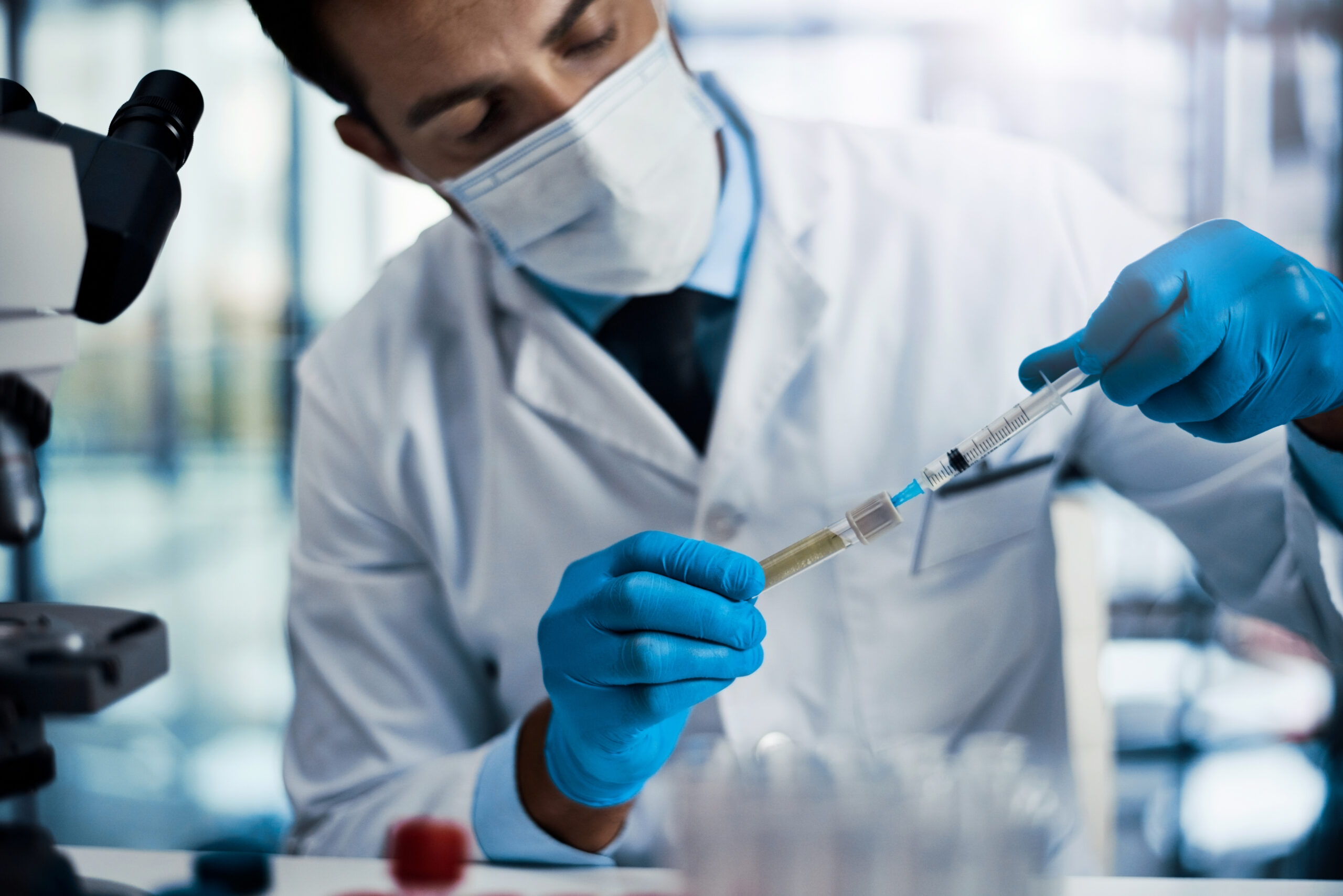 Healthcare professional preparing a syringe and injectable solution in a clinical setting.